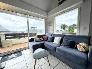 ein Wohnzimmer mit einem blauen Sofa und großen Fenstern in der Unterkunft Charmant T3 duplex 2 Bord de mer Terrasse in Quiberon