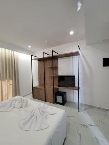 a bedroom with a white bed and a television at Prestige Hotel in Ksamil