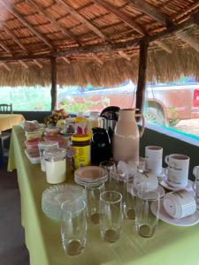 una mesa con tazas, platos y vasos. en Pousada Capim Dourado Jalapão São Felix TO, en São Félix do Tocantins