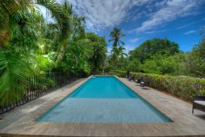 a swimming pool in a yard with chairs and trees at Waterfront Pink House with Private Dock & Pool in Captiva