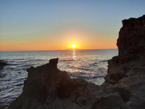 a sunset over the ocean with rocks in the foreground at All seasons holiday in El Haouaria