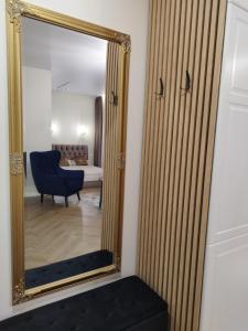 a mirror in a living room with a blue chair at Old street apartment in Šiauliai