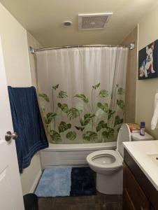 a bathroom with a toilet and a shower curtain at Stylish Downtown Calgary Home in Calgary