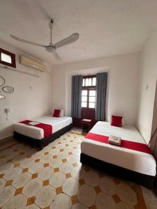 a bedroom with two beds and a window at Hotel Margarita in Mérida