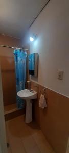 a bathroom with a sink and a blue shower curtain at Cafaro in San Miguel de Tucumán