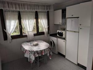 una pequeña cocina con mesa y nevera en Villa en la costa, en Santander