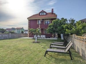 una casa púrpura con dos bancos en un patio en Villa en la costa, en Santander