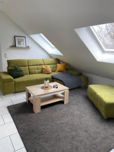ein Wohnzimmer mit einem grünen Sofa und einem Couchtisch in der Unterkunft Ferienwohnung am Erbacher Mümlingufer in Erbach