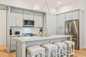 a kitchen with white cabinets and a large island with bar stools at Ship Island Town Home in Pass Christian