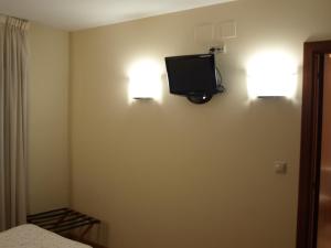 1 dormitorio con TV en la pared y 1 cama en Pension Viella Asturias en Viella