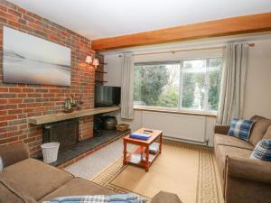a living room with a fireplace and a brick wall at Swan Dyke Cottage in Horning