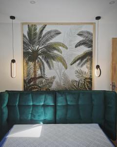 eine grüne Couch vor einer Wand mit einem Palmenmilch in der Unterkunft Villa au porte de montchat Lyon in Bron