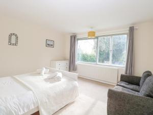 a bedroom with a bed and a chair and a window at Swan Dyke Cottage in Horning