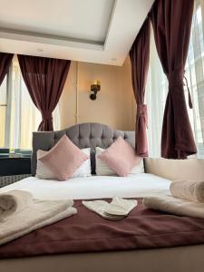 a large bed with pink and white pillows and curtains at Asmali Pera Hotel in Istanbul