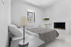 a white bedroom with a bed and a fireplace at Amor de Verano in Spetses