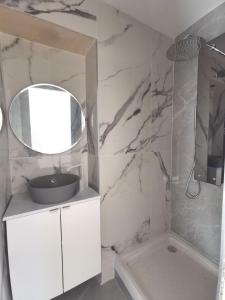 ein weißes Badezimmer mit einem Waschbecken und einem Spiegel in der Unterkunft Villa au porte de montchat Lyon in Bron