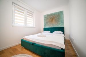 a bedroom with a large bed with a green headboard at Apartment Vila Idila in Tuzla