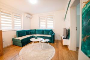 ein Wohnzimmer mit einem grünen Sofa und einem Tisch in der Unterkunft Apartment Vila Idila in Tuzla