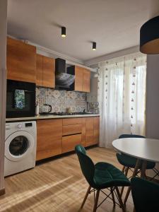 uma cozinha com uma máquina de lavar roupa, uma mesa e cadeiras em House of flowers em Petroşani