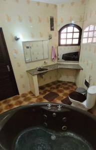 a bathroom with a black tub and a sink at Nana's House Vilas in Lauro de Freitas