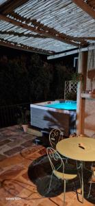 um pátio com uma mesa e cadeiras e uma piscina em A Pasturella, jacuzzi privé em Venzolasca