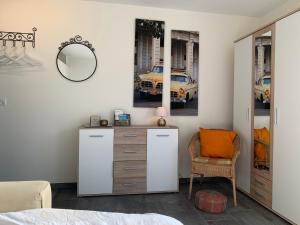 a bedroom with a dresser and a mirror and a chair at Chez Svanette B&B Villa Sonnglück in Zullwil