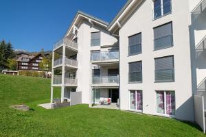 an exterior view of a white building with a green yard at Sunnewies in Wildhaus