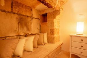 Bett mit Kissen in einem Zimmer mit einer Steinmauer in der Unterkunft Palazzo Le Zicaredde in Salve