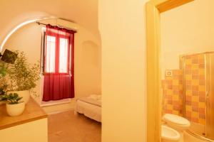 ein Bad mit einem WC und einem roten Fenster in der Unterkunft Palazzo Le Zicaredde in Salve