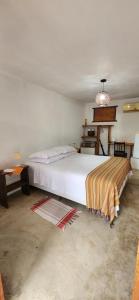 um quarto com uma grande cama branca num quarto em Suítes da Quinta dos Samaniegos em Itaúnas