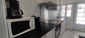 eine Küche mit einer Mikrowelle und einer schwarzen Arbeitsplatte in der Unterkunft Berthe Lydie Cottage Charme, Confort et Mer in Fort-Mahon-Plage