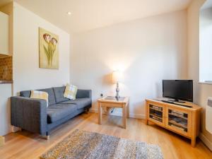 uma sala de estar com um sofá azul e uma televisão em The Burcott Inn Cottages em Wells