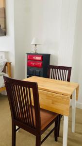 120 Mortimer St, Herne Bay في Kent: طاولة خشبية مع كرسيين وخزانة حمراء