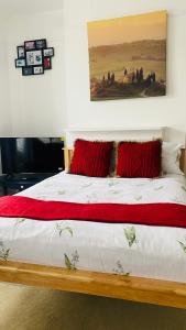 ein Bett mit roten Kissen und einem Gemälde an der Wand in der Unterkunft 120 Mortimer St, Herne Bay in Kent