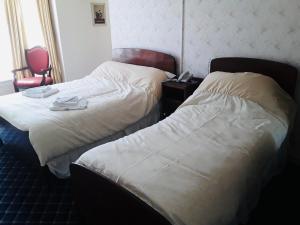 a hotel room with two beds and a chair at Royal Hotel Great Yarmouth in Great Yarmouth