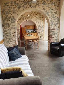 een woonkamer met een tafel en een stenen muur bij GITE LES ARCHES in Saint-Andéol-le-Château