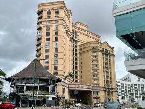 a tall building with a gazebo in front of it at Cozzzy hut Riverbank Suites Kuching with spectacular River view in Kuching