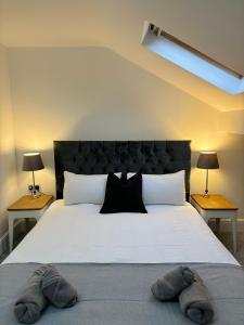 una camera da letto con un grande letto con due pantofole sopra di Cardiff/Pernath Home2 a Cardiff