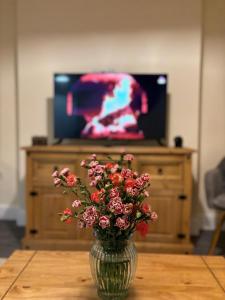 un vaso di fiori seduto su un tavolo con una tv di Cardiff/Pernath Home2 a Cardiff