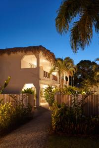 una casa blanca con una valla y palmeras en Empyrean Tropical Wellness Portillo en Las Terrenas