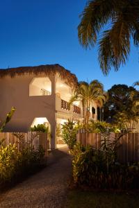 a white house with a fence and palm trees at Empyrean Tropical Wellness Portillo in Las Terrenas