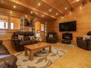 a living room with leather furniture and a flat screen tv at Chywolow Lodge in Morvah