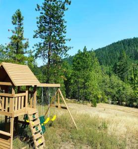 a playground with a slide and a swing at Majestic newly renovated home surrounded by greenery in Grants Pass