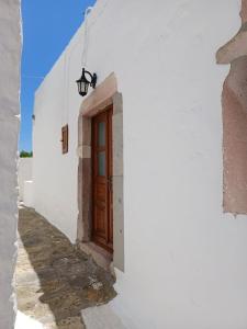 a white building with a wooden door on a street at Σπιτι Χωρα Πατμου in Patmos