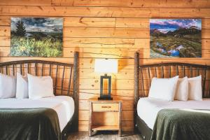 two beds in a room with wooden walls at Lakeside Lodge Resort and Marina in Pinedale