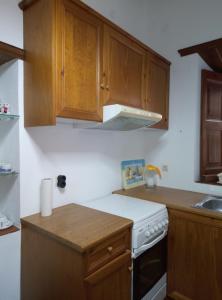 a kitchen with wooden cabinets and a white stove top oven at Σπιτι Χωρα Πατμου in Patmos