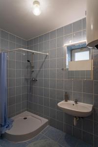 y baño de azulejos azules con lavabo y ducha. en Forrás Vendégház Maconka, en Bátonyterenye