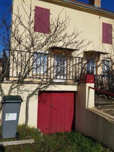 a building with two red doors and a tree at Appartement RDC avec terrasse in Épinac-les-Mines