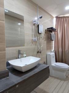 uma casa de banho com um lavatório branco e um WC. em The Patioz Boutique Hotel em Kajang