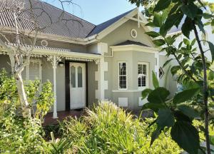 a white house with a white door and some bushes at Laurel Cottage in Franschhoek